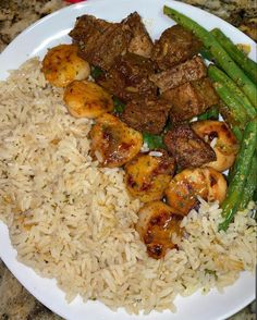 a white plate topped with rice and meat next to green beans on top of a counter