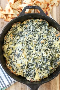 spinach and cheese pizza in a cast iron skillet on a wooden table with pita chips