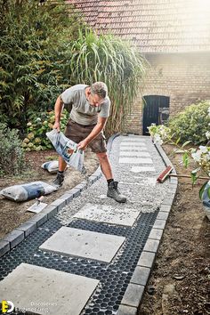 a man laying on the ground in front of a house with cement blocks and tools