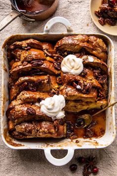 a casserole dish with pecans and whipped cream