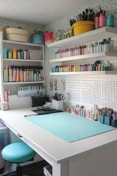 a sewing room with lots of crafting supplies on the wall and shelves above it