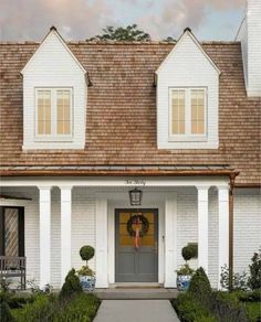 a white house with brown shingles and two front doors