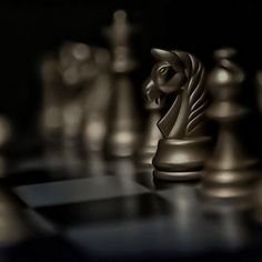 a chess board with gold and silver pieces on it's surface, including a horse head