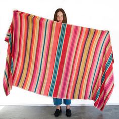 a woman holding up a colorful striped blanket