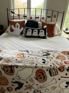 a bed with halloween decorations on it in front of a window and two pumpkins