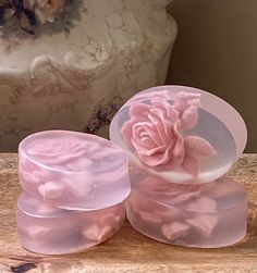 three plastic containers with pink flowers on them sitting on a wooden table next to a vase