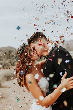 a newly married couple kissing under confetti