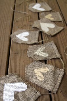 some burlap hearts are hanging on a wooden table