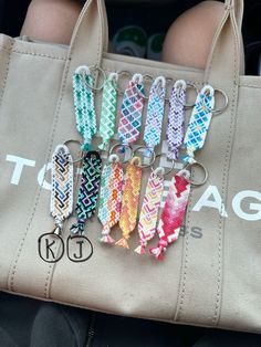 a person holding a bag with six different key chains attached to it's handles