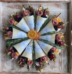 an arrangement of fruits and flowers arranged in a circle on top of a wooden tray