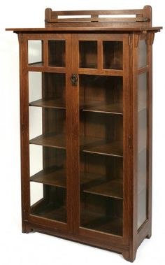 a wooden bookcase with glass doors on the top and bottom shelves, in front of a white background