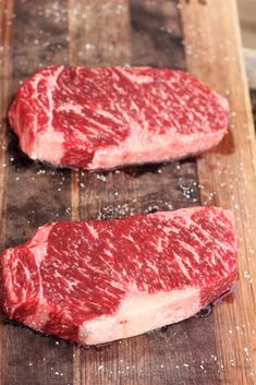 two pieces of raw meat sitting on top of a cutting board next to each other