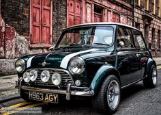 an old black and white car parked on the street