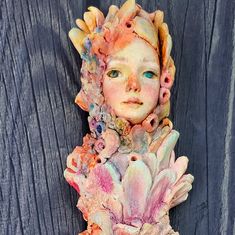 a close up of a statue on a wooden surface with blue eyes and pink hair