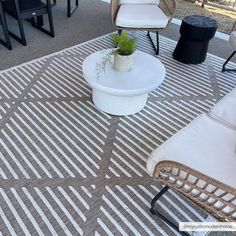 an outdoor area with chairs, tables and a potted plant on the rugs