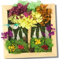 a wooden frame with flowers and plants in the shape of a tree on top of grass