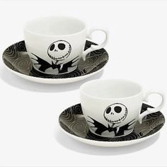 two cups and saucers decorated with jack skellingy faces