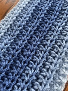 a close up view of a blue and gray crocheted rug on a wooden floor