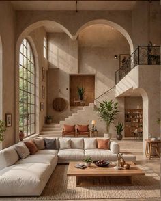 a living room filled with lots of furniture next to a stair case in front of a window