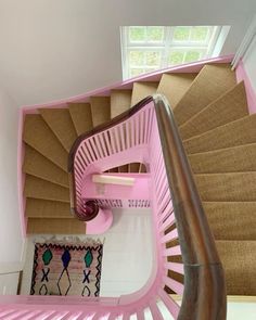 a pink spiral staircase in a house with carpet on the floor and handrails