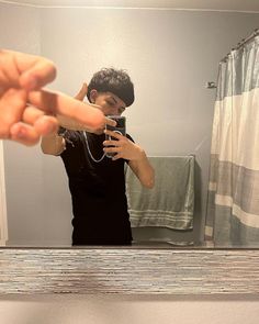 a man taking a selfie in front of a bathroom mirror with his hand pointing at the camera