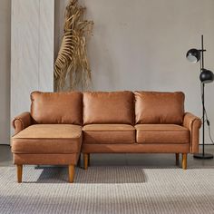 a brown leather couch sitting on top of a carpeted floor next to a lamp