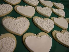 decorated cookies arranged in the shape of hearts on a green tablecloth with white icing