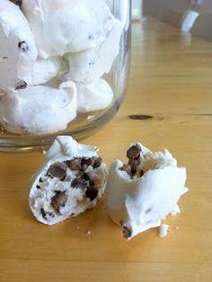 a glass jar filled with white marshmallows on top of a wooden table