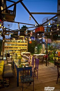 an outdoor restaurant with lots of tables and chairs on the outside patio, lit up at night