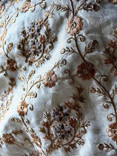 an embroidered fabric with gold and purple flowers on it, as well as other decorative items