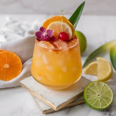 an orange cocktail with garnishes and limes sits on a marble coaster