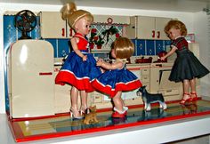 two dolls are playing with a dog in the kitchen