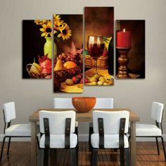 a dining room table with four pieces of art on the wall and candles in vases