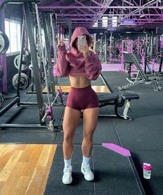 a woman taking a selfie in a gym with her phone up to her ear