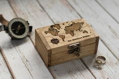 a wooden box sitting on top of a white table next to a compass and ring