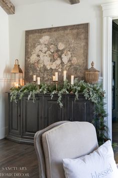 a living room decorated for christmas with candles on the fireplace mantel and floral arrangement