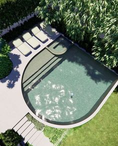 an aerial view of a swimming pool surrounded by greenery and trees with lounge chairs around it