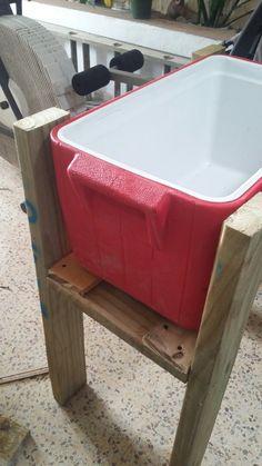 a red and white cooler sitting on top of a wooden stand