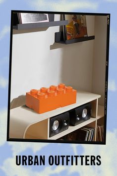 an orange lego block sitting on top of a white table next to a book shelf