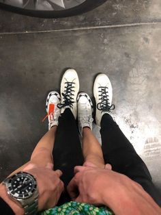 two people standing next to each other with their feet on the ground and one person wearing white shoes