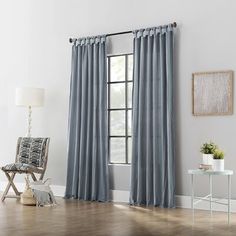 a living room with white walls and blue curtains on the window sill, hardwood flooring