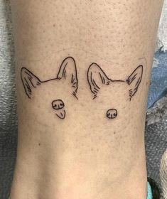 a tattoo on the foot of a woman with two dogs'heads drawn on it