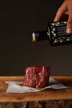 a person pouring mustard into a piece of meat