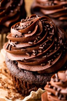 chocolate cupcakes with chocolate frosting and sprinkles on top are shown