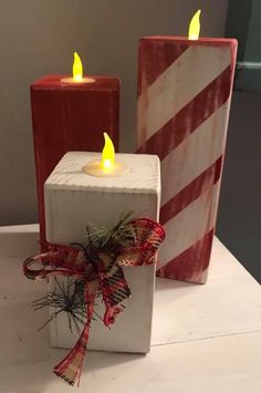 two red and white candles sitting next to each other on top of a wooden block