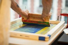 a person using a wood block to make a piece of art on a wooden table