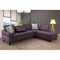 a living room with a purple sectional couch and pillows on the floor next to a lamp