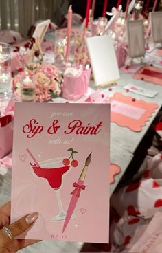 a person holding up a card for a sip and paint party with hearts on the table