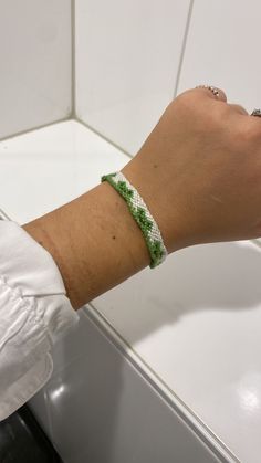 a person's arm with a bracelet on it and a white wall in the background