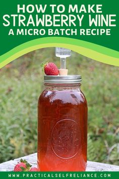 a mason jar filled with strawberry wine sitting on top of a table next to strawberries